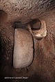 La minuscule loge de garde se trouve au-dessus du couloir d’accès et des trous de visée creusés vers le bas débouchent dans le plafond de la galerie juste devant la porte de pierre. Grâce à ce dispositif, un défenseur pouvait anéantir les assaillants bloqués devant la porte de pierre ; ville souterraine de Özkonak (Cappadoce, Turquie). Cappadoce 
 Turquie 
 loge de garde 
 meurtrière 
 trou de visée 
 ville souterraine 
 Özkonak 