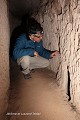 Dans ce couloir d’accès, deux trous de visée débouchent près du sol juste avant une première meule de fermeture ; ville souterraine de Saratli (Cappadoce, Turquie). Cappadoce 
 Saratli 
 Turquie 
 meurtrière 
 trou de visée 
 ville souterraine 