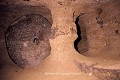 Porte de pierre maintenue par un pilier préservé dans la roche et percée d’un judas central ; ville souterraine de Sivasa (Gökçetoprak, Cappadoce, Turquie). Cappadoce 
 Sivasa 
 Turquie 
 meule 
 ville souterraine 