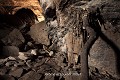 Dans la grotte, le fétiche est appuyé contre une paroi ; des crânes, des cornes et des mandibules sont accrochés aux cordes et des plumes sont collées sur la roche par le sang des sacrifices (Tanéka-Koko, Donga, Bénin). Afrique de l'Ouest 
 Bénin 
 Dahomey 
 Donga 
 Tanéka Koko 
 fétiche 
 grotte 
 rite 
 rituel 
 sacré 
 souterrain 