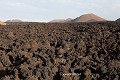 Les montagnes du feu (Montañas del Fuego) se composent de plusieurs cônes volcaniques apparus lors de la gigantesque éruption de 1730-1736. La coulée au premier plan date de cette époque et provient de la Montaña Rajada visible au fond à gauche ; Parc national de Timanfaya (Lanzarote, Canaries). Canaries 
 Lanzarote 
 Montaña Rajada 
 Montañas del Fuego 
 Timanfaya 
 basalte 
 coulée de lave 
 lave 
 montagnes du feu 
 vocanisme 
 volcan 
 volcanique 