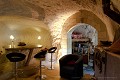 Dans cette cave demeurante de plaine, l’imposant poêle à bois est installé dans la salle à manger ; la chambre à coucher s’ouvre juste derrière. La maison fonctionne en autonomie, sans raccordement au réseau électrique et à l’eau. Cave restaurée dans les années 2000 (Saumurois, France). [1152N042 © Laurent Triolet/www.mondesouterrain.fr] Loire 
 Roche 
 Saumur 
 Saumurois 
 Val de Loire 
 cave 
 maison creusée 
 troglodyte 
 troglodytique 
 tuffeau 